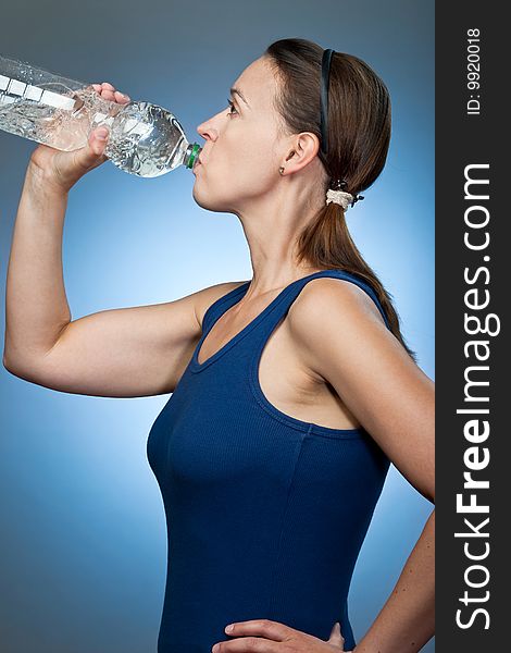 A young sporty woman drinking from a bottle of mineral water. A young sporty woman drinking from a bottle of mineral water.