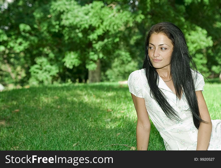 Pretty girl in a park sitting down and smiling. Pretty girl in a park sitting down and smiling