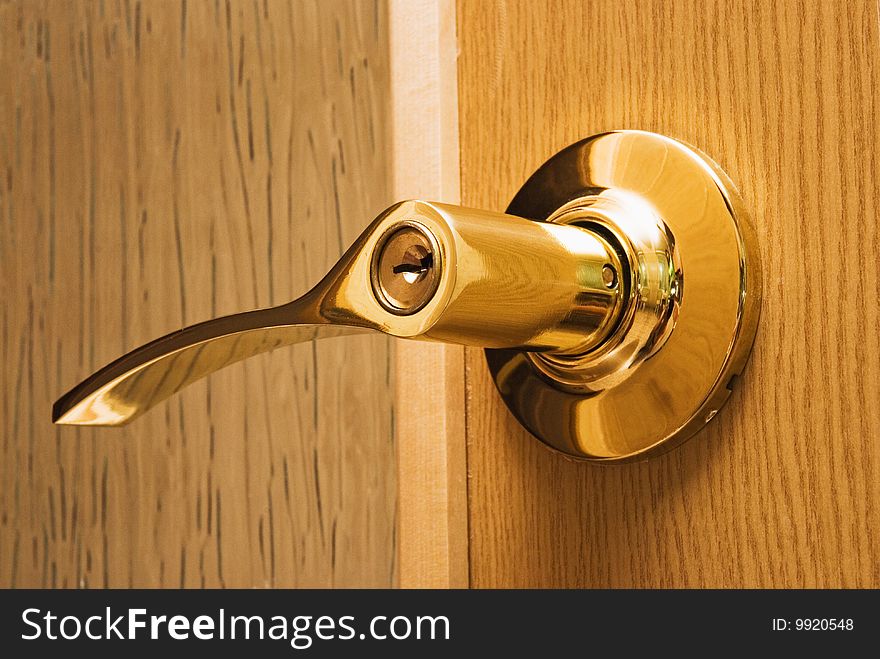 Shiny metal knob with a lock and key in a wooden door. Shiny metal knob with a lock and key in a wooden door