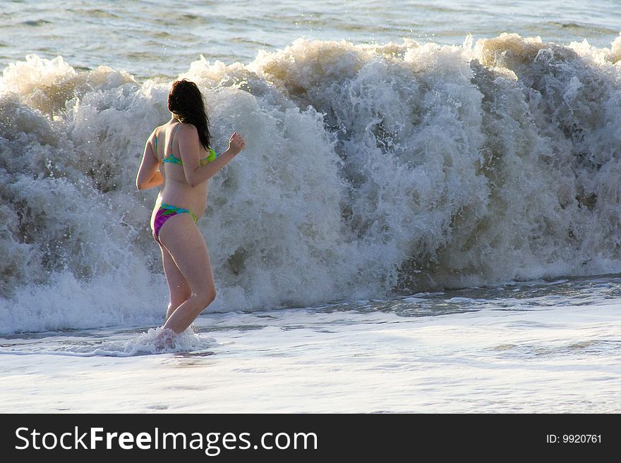 A girl is running from the wave at the shore of the Black sea. A girl is running from the wave at the shore of the Black sea