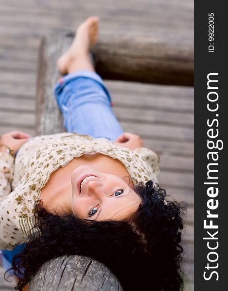 Outdoor portrait of beautiful brunet woman lying on wooden floor