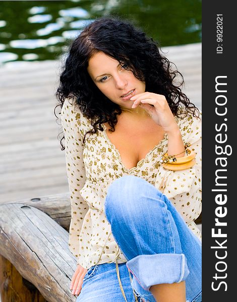 Beautiful brunet woman sitting near the water