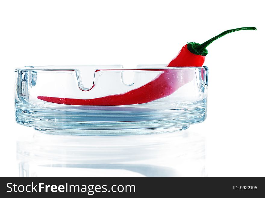 Red chili pepper on glass ashtray isolated on white