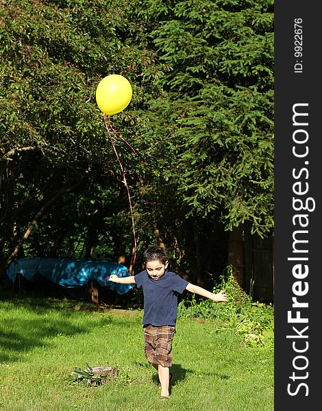 Adorable six year old boy playing with yellow balloon. Adorable six year old boy playing with yellow balloon.