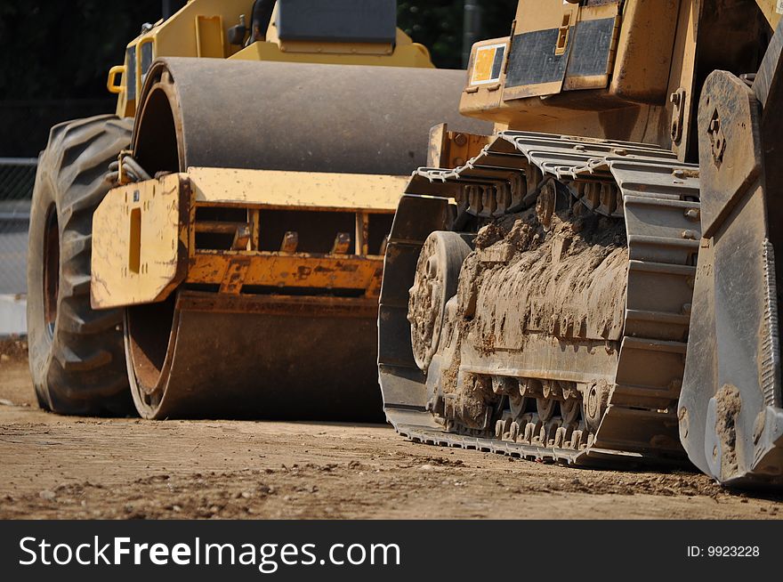 Two yellow construction vehicles sit in line with each other on a jobsite. Two yellow construction vehicles sit in line with each other on a jobsite.