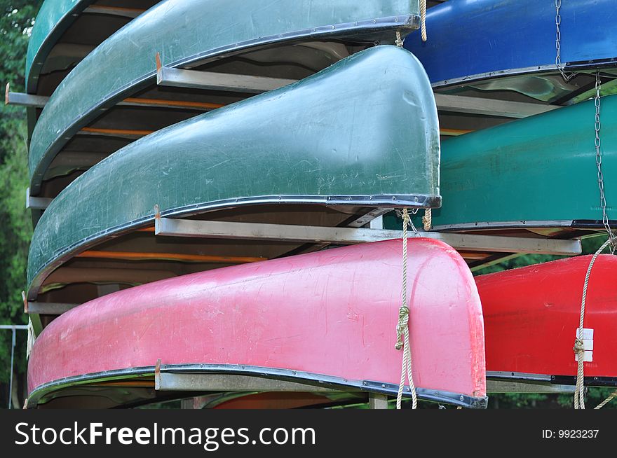 Colorful kayaks are stacked above each other on a rack. Colorful kayaks are stacked above each other on a rack.