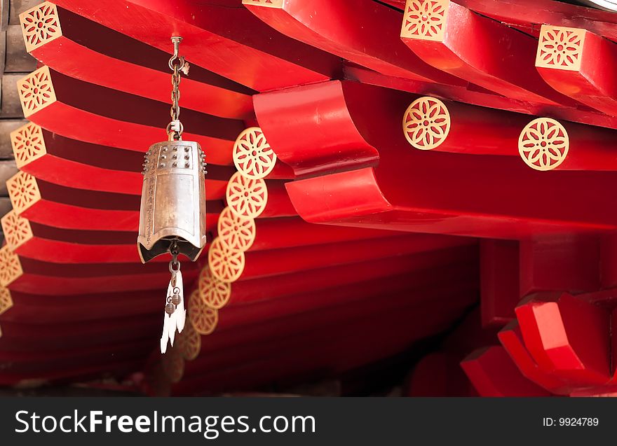 A brass bell with a bat shaped clapper hanging at the corner of the roof of a Buddhist temple build in classical Chinese architectural style, in Chinatown, Singapore. A brass bell with a bat shaped clapper hanging at the corner of the roof of a Buddhist temple build in classical Chinese architectural style, in Chinatown, Singapore