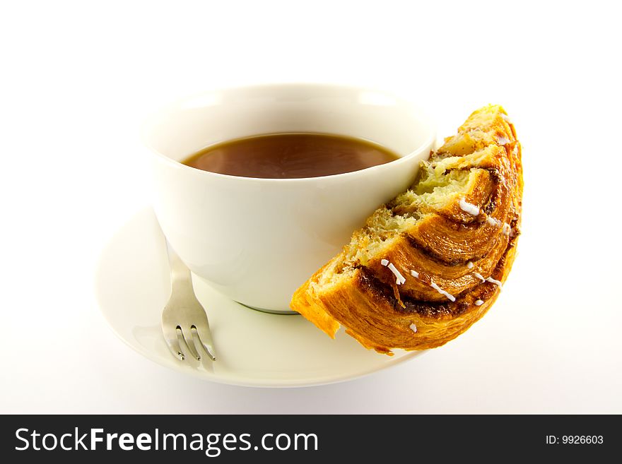 Half a cinnamon bun with a cup of tea and fork with clipping path on a white background. Half a cinnamon bun with a cup of tea and fork with clipping path on a white background