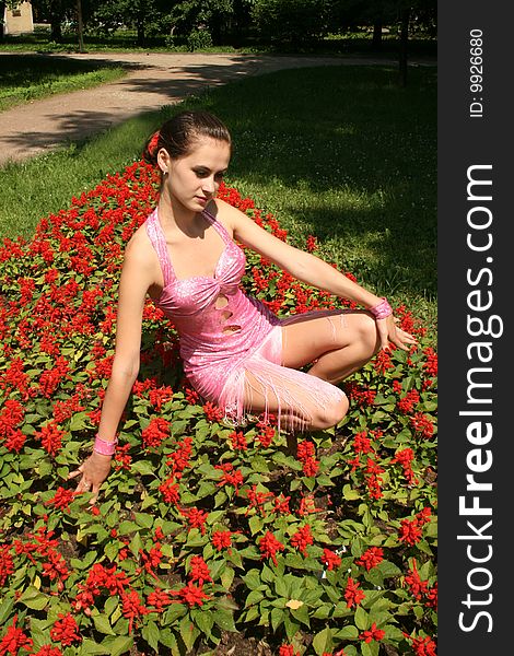 Pretty girl sitting among flowers in a park