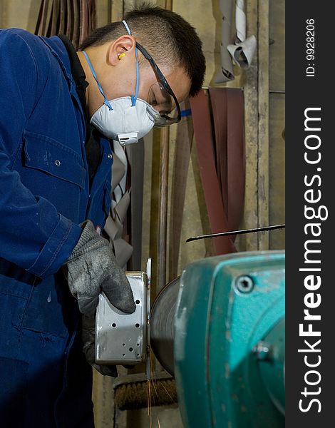 Man using electric polisher on stainless steel box in workshop. Man using electric polisher on stainless steel box in workshop