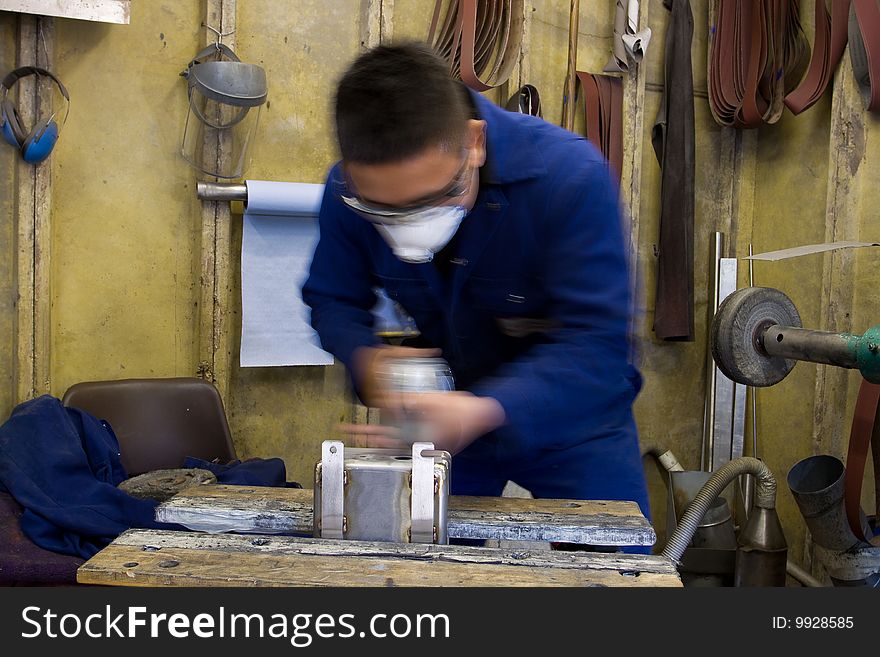 Man using electric polisher on stainless steel box in workshop. Man using electric polisher on stainless steel box in workshop