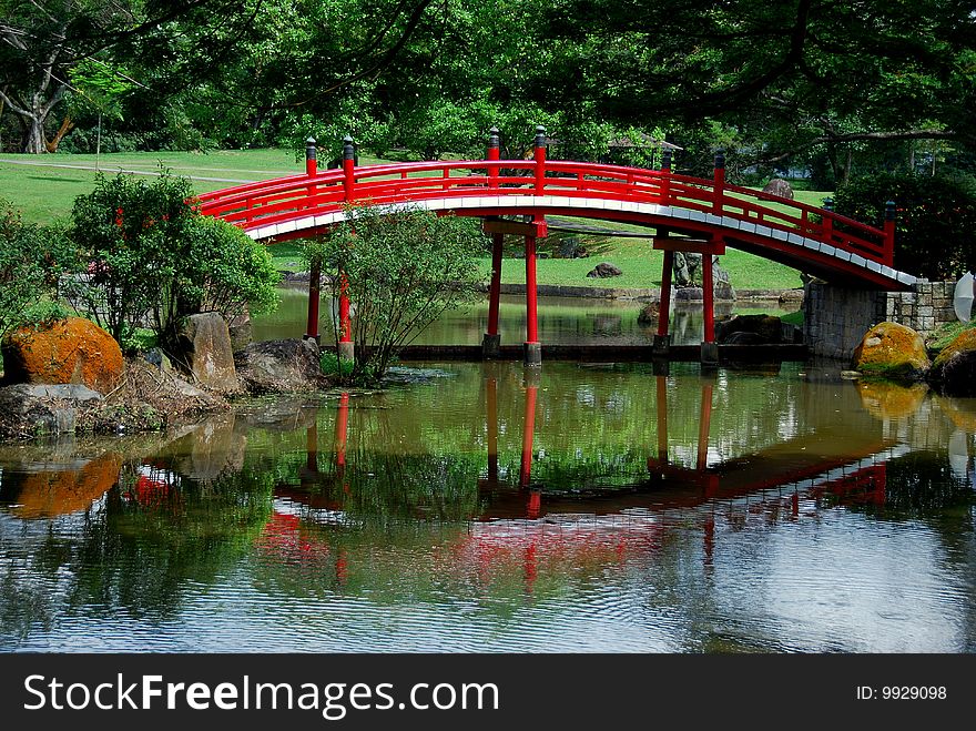 A traditional Japanese wooden bridge is reflected in the quiet waters of a lagoon in the blissful Japanese Garden - Xu Lei Photo / Lee Snider Photo Images. A traditional Japanese wooden bridge is reflected in the quiet waters of a lagoon in the blissful Japanese Garden - Xu Lei Photo / Lee Snider Photo Images.