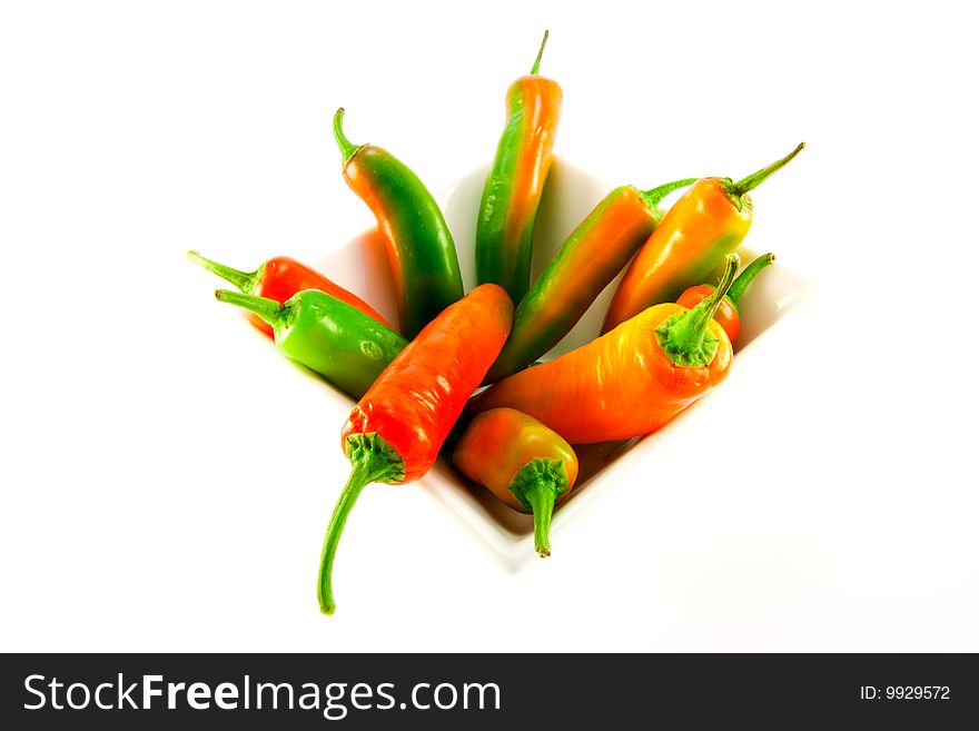 Red and green chillis in a white square bowl with clipping path on a white background. Red and green chillis in a white square bowl with clipping path on a white background