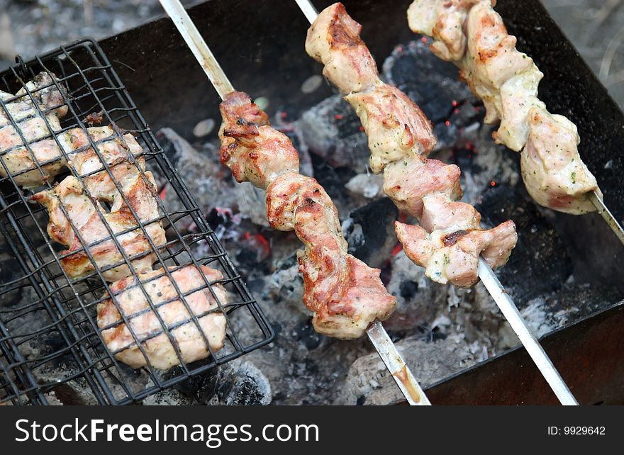 Shish kebab roasting on an open fire to background