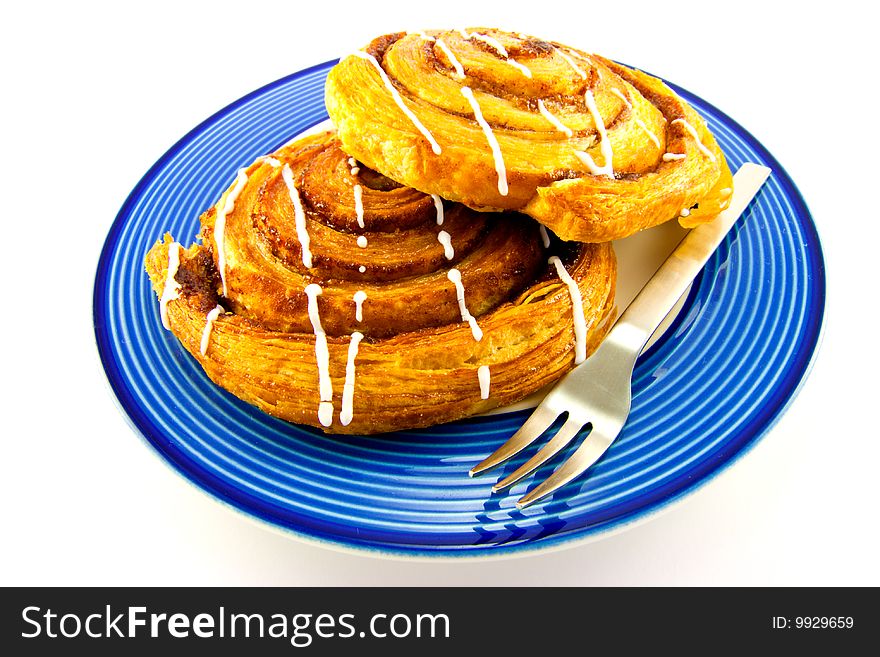 Two cinnamon buns on a blue plate with fork with clipping path on a white background