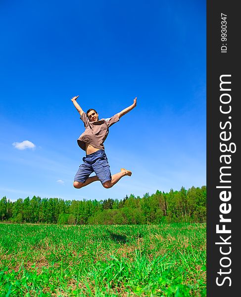 Man jumping on a green meadow with a beautiful  sky. Man jumping on a green meadow with a beautiful  sky