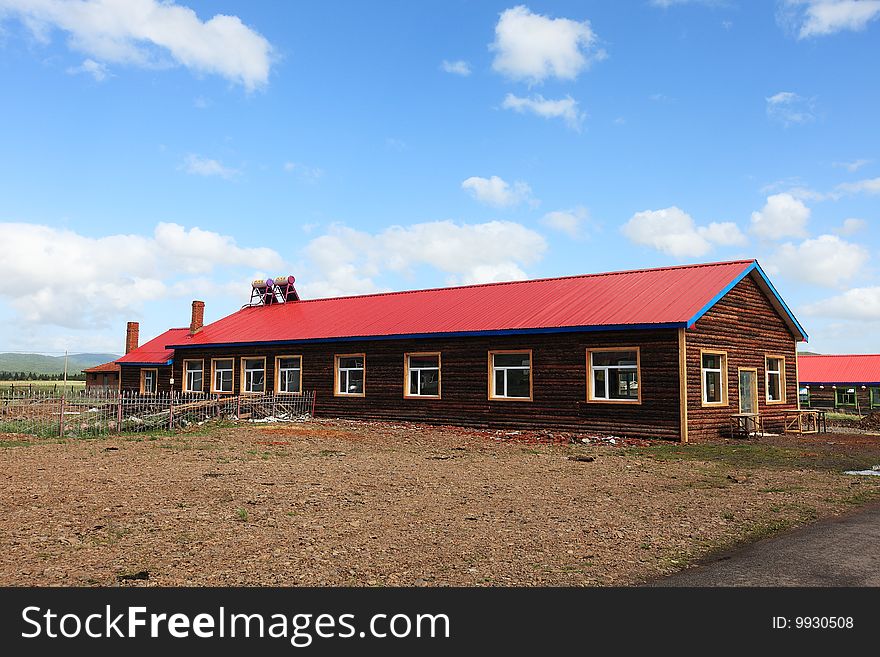 Wood house with red roof on grassland