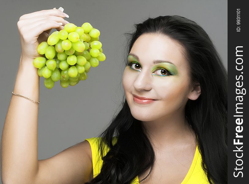 Portrait of young brunette with green grapes. Portrait of young brunette with green grapes