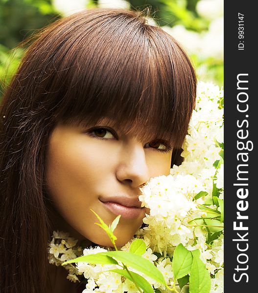 Young woman near blossoming flowers. Summer garden. Young woman near blossoming flowers. Summer garden.