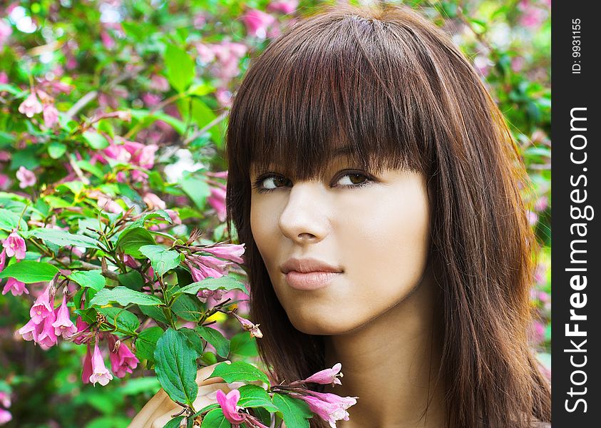 Young woman near blossoming flowers. Summer garden. Young woman near blossoming flowers. Summer garden.