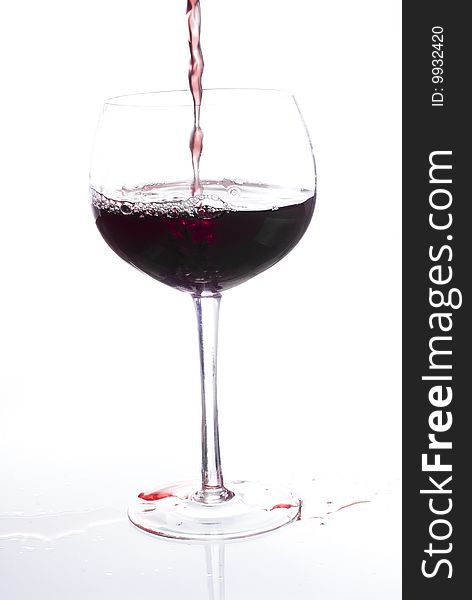 Red wine being poured into a wine glass. Red wine being poured into a wine glass.