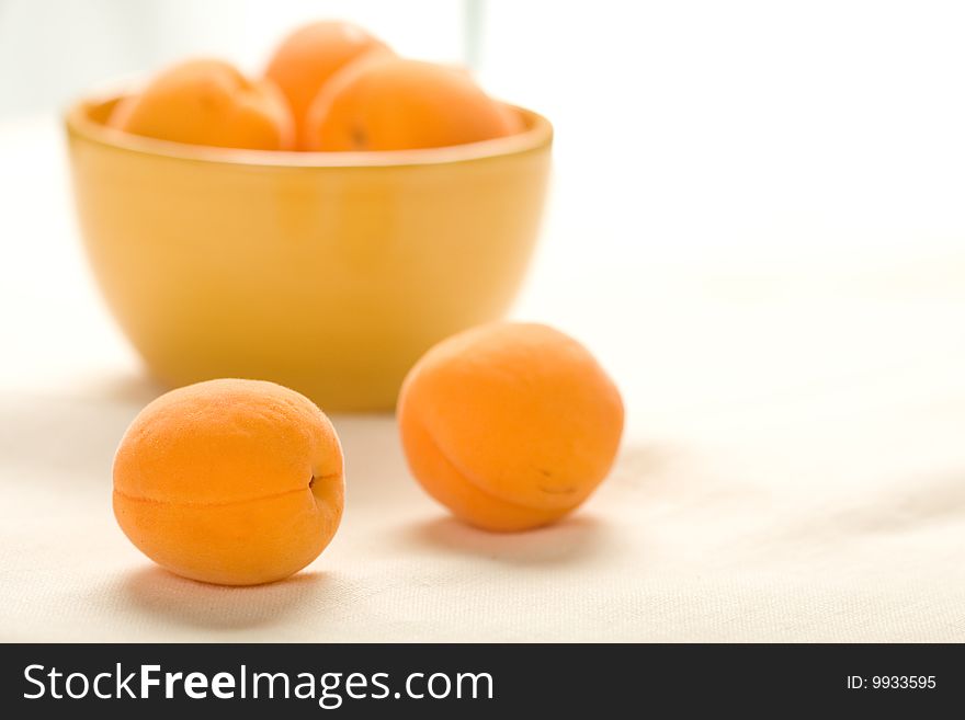 Apricots in yellow bowl on linen table cloth wrinked to show texture at low depth of field