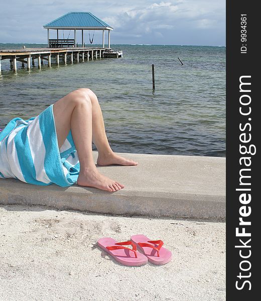 Pink sandals at the feet of a sunbather at the water's edge in the Gulf of Mexico.