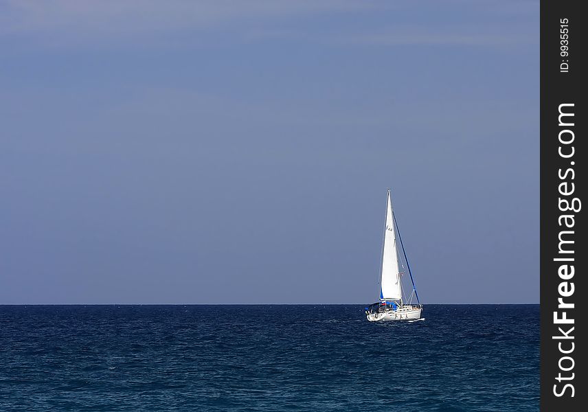 White sailboat floating on the blue sea