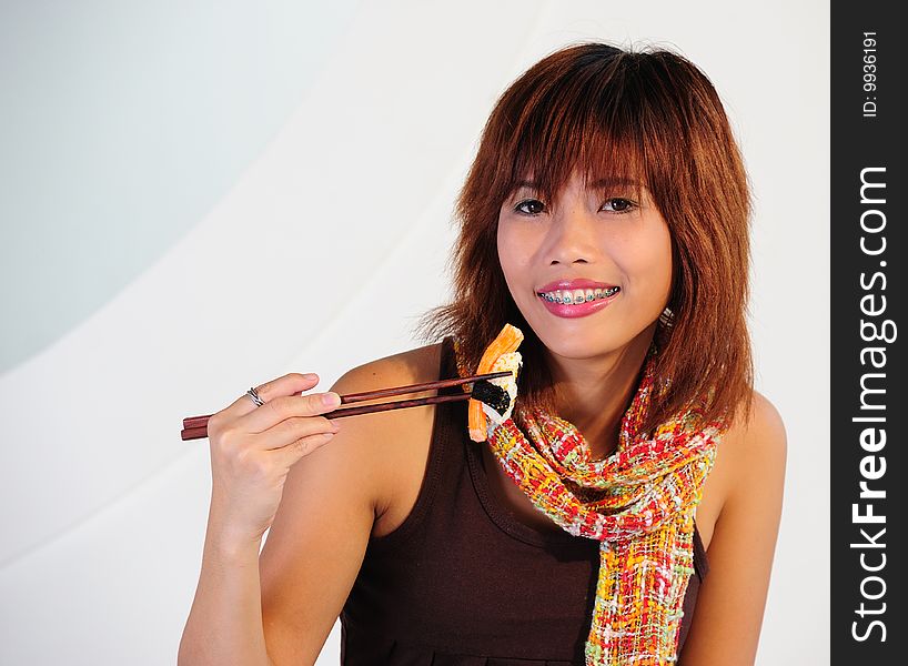 Very seductive young asian woman eating sushi on a white background