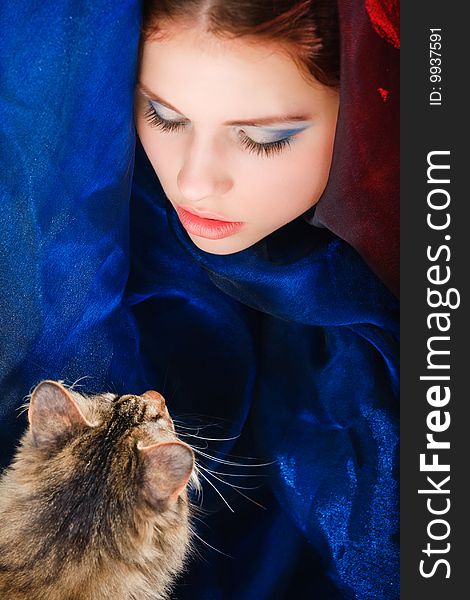 Young girl face in blue fabric with a cat. Young girl face in blue fabric with a cat
