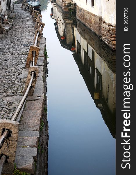 The stone road is full of peaceful,with a beautiful reflection in the river.This photo taked in a traditional chinese village. The stone road is full of peaceful,with a beautiful reflection in the river.This photo taked in a traditional chinese village.