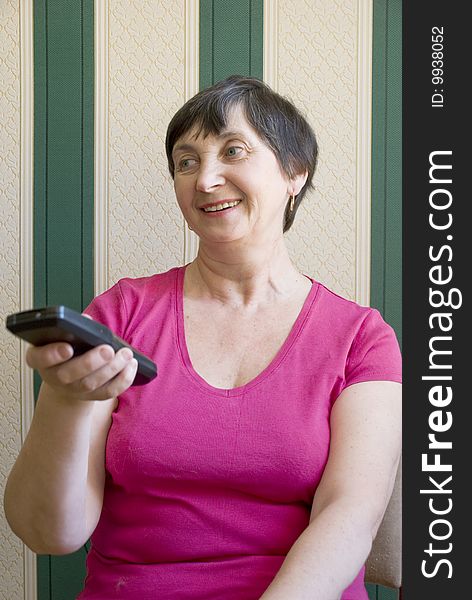 Aged woman changing channels with clicker. Aged woman changing channels with clicker