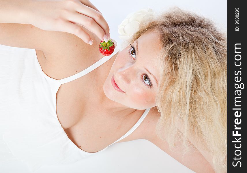 Young woman in white dress eating strawberries