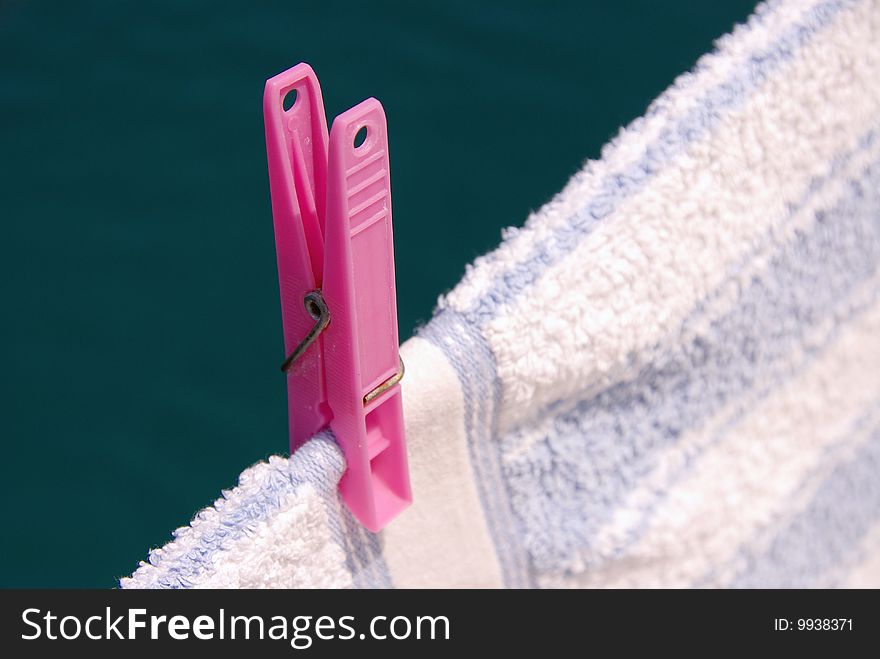 A pink clothespin at a towel. A pink clothespin at a towel