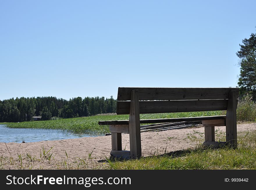 Landskape containing wooden chair on the sunny summer beach.