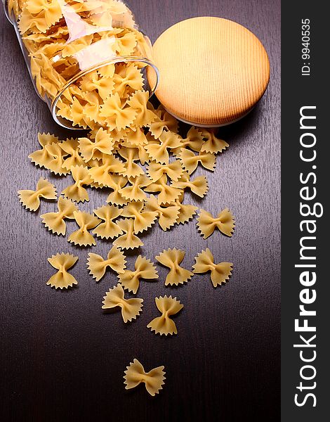 Farfalle pasta with glass isolated on black surface