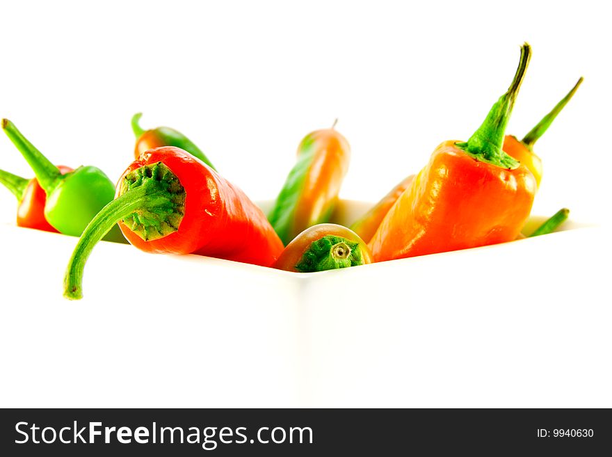 Red and green chillis in a white square bowl with clipping path on a white background. Red and green chillis in a white square bowl with clipping path on a white background