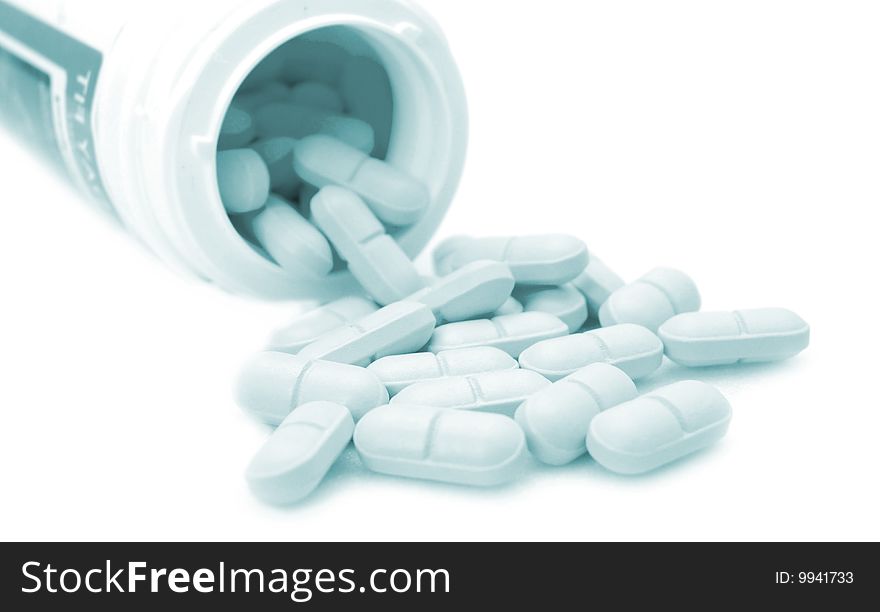 Pills from bottle on white bg