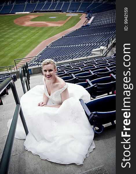 Model wearing wedding gown posed in a baseball stadium. Model wearing wedding gown posed in a baseball stadium.