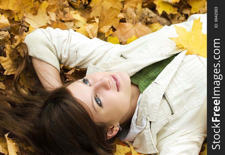 Beautiful girl lying on autumn maple leaves outdoors. Beautiful girl lying on autumn maple leaves outdoors