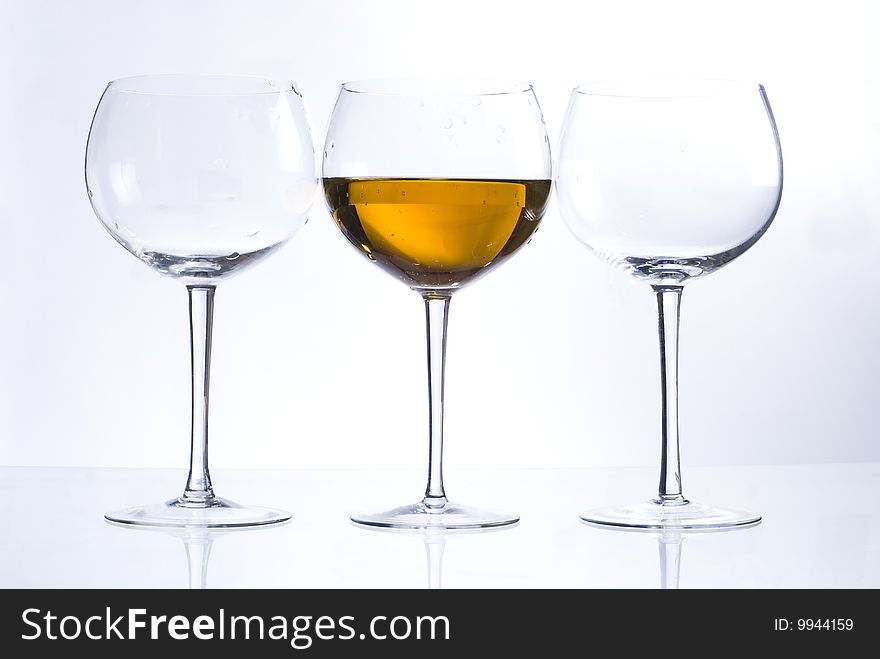 Shot of two empty glasses and one glass with wine. Shot of two empty glasses and one glass with wine.