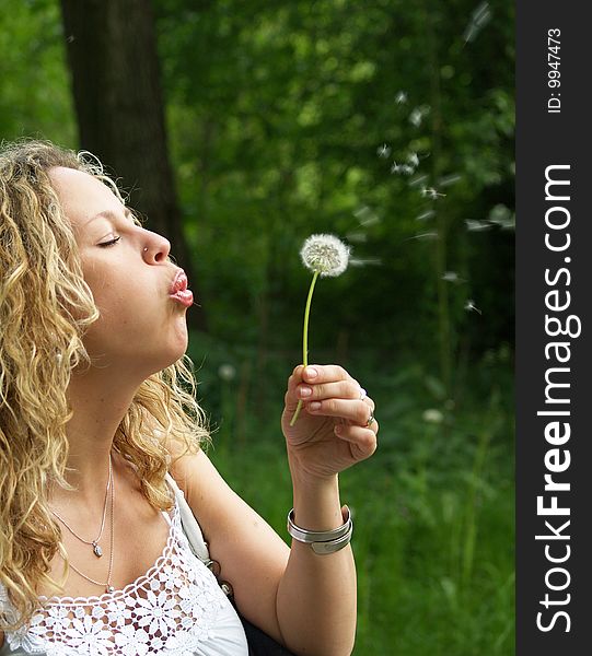 Curly girl blows flying dandelion seed. Curly girl blows flying dandelion seed