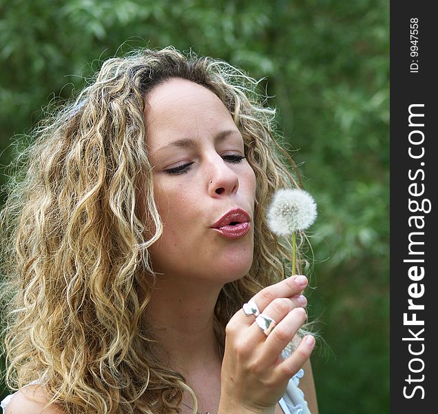 Curly girl blows flying dandelion seed. Curly girl blows flying dandelion seed