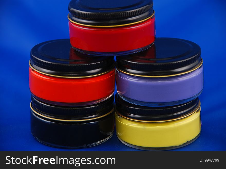 Five paint bottles of glass in different colors on a blue background. Five paint bottles of glass in different colors on a blue background