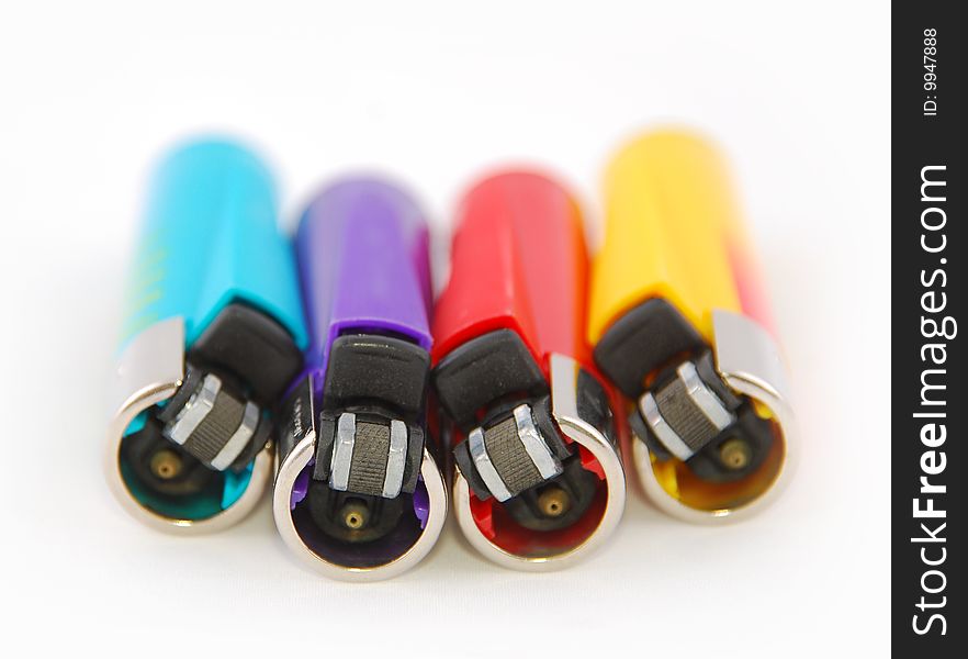 Four lighters in different colors on a white background with a shallow depht of field. Four lighters in different colors on a white background with a shallow depht of field