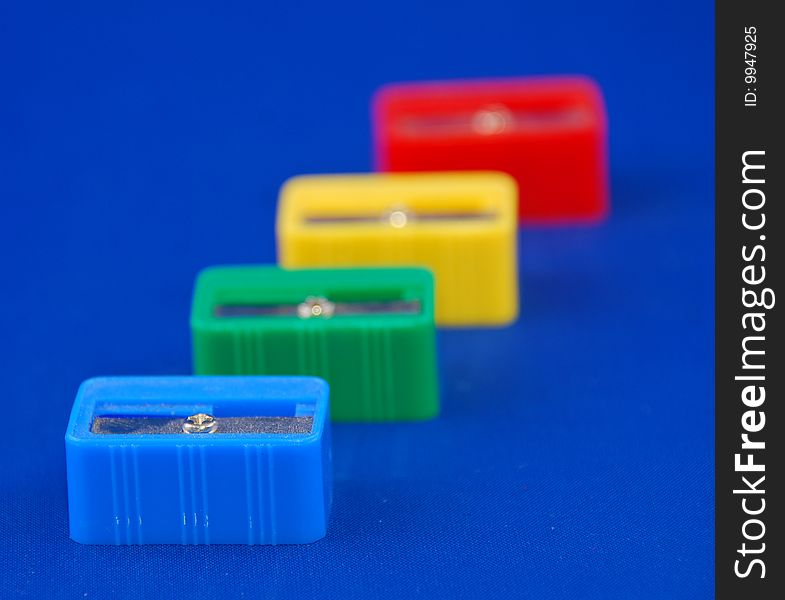 Pen sharpeners in different colors on blue background with shallow depht of field