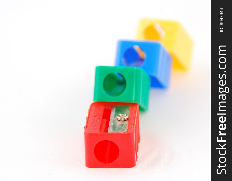 Four pen sharpeners in different colors on a white background with a shallow depht of field