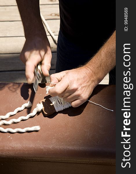 A sailor rigging, tying and cutting cables, in a classic wooden sailing ship, using a sailor’s hand knife. A sailor rigging, tying and cutting cables, in a classic wooden sailing ship, using a sailor’s hand knife