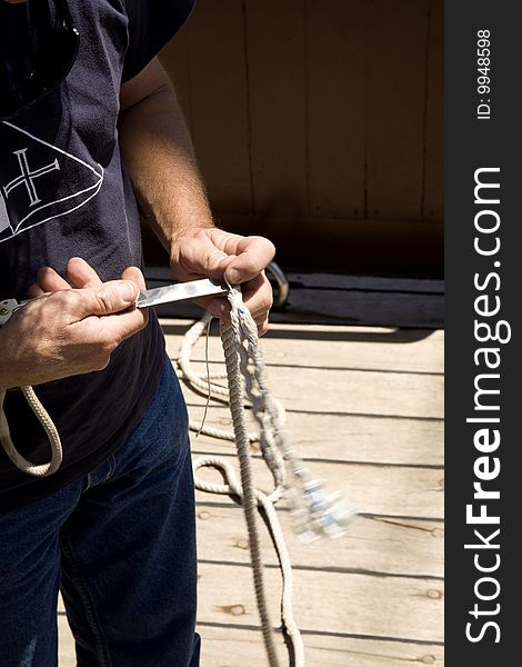 Sailor cutting cables in a ship's deck