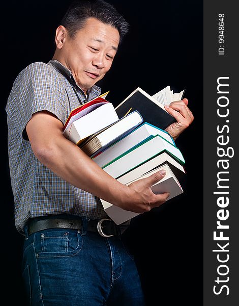 An asian student with many books dropping them - on a dark background. An asian student with many books dropping them - on a dark background.